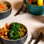 Delicious colorful bowls of salad and fresh beverages on a white table, perfect for healthy dining.